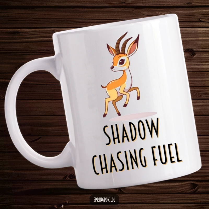 Funny springbok mug shows a playful springbok character joyfully chasing its own shadow, full of energetic humor.