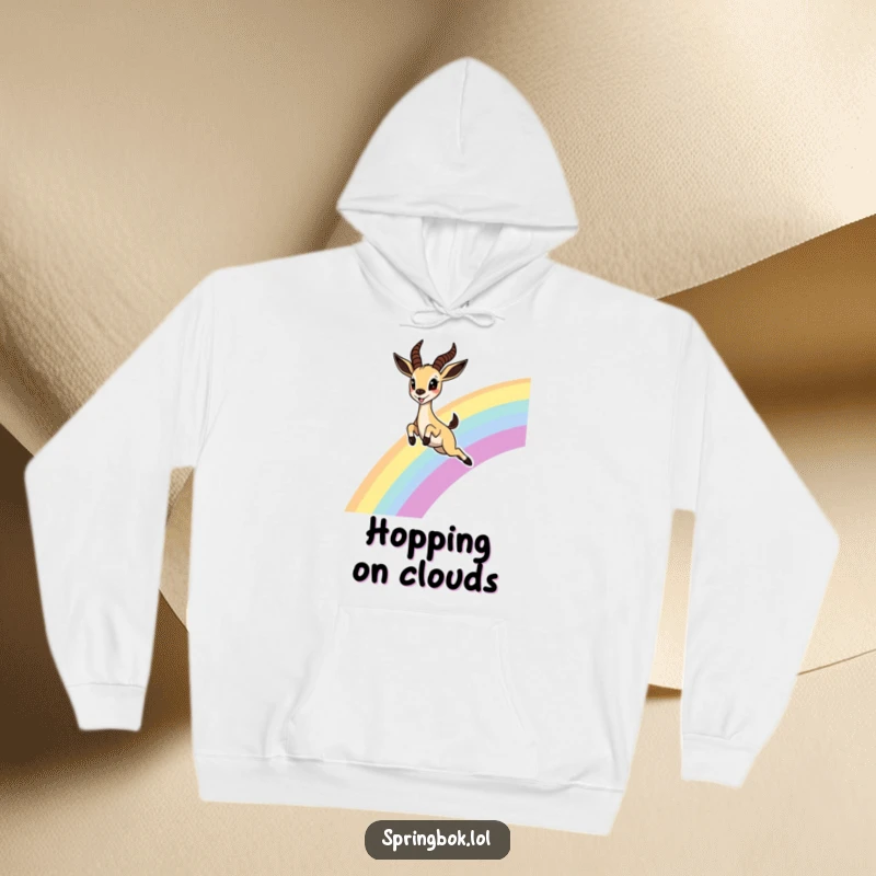 Funny Springbok Rainbow Hoodie, illustrating a cute springbok joyfully leaping over a rainbow with delighted eyes, ideal for cozy enchantment.