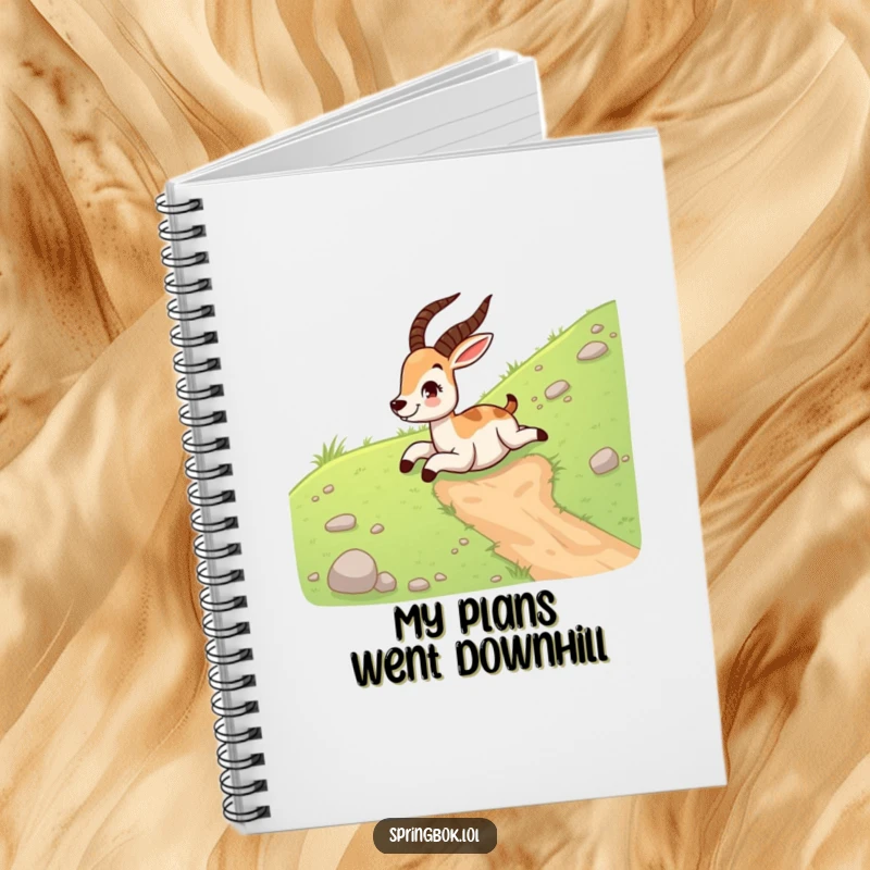 Funny springbok notebook depicting a happy springbok sliding down a grassy hill on its belly, ideal for writing down ideas.